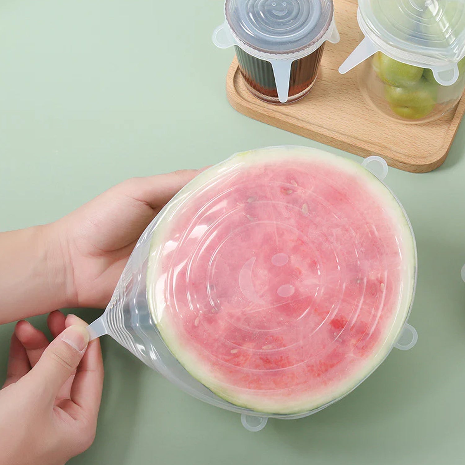 Variety of Tidy Table silicone lids stretched over different food containers and a cut fruit.