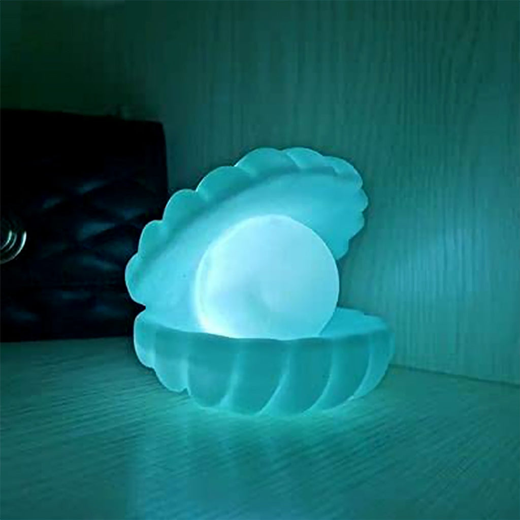 The Pearl Shell Night Lamp placed on a wooden desk next to a plant, enhancing the room's ambiance.