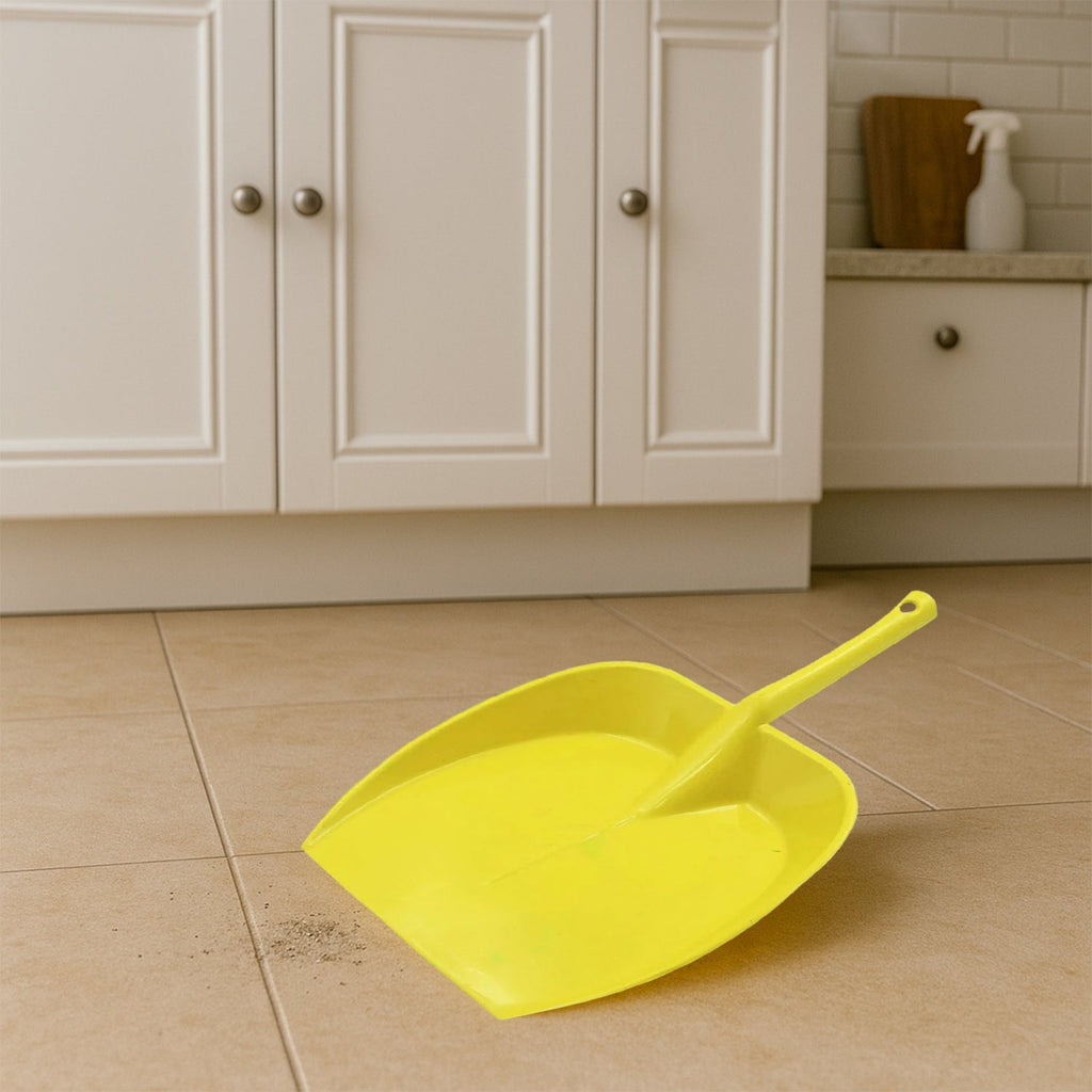 Long handle dustpan positioned on a tiled floor, demonstrating effective dust collection.