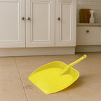 Long handle dustpan positioned on a tiled floor, demonstrating effective dust collection.