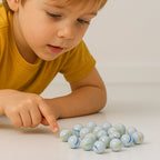 Box showcasing approximately 30 white glass marbles with colorful swirl patterns