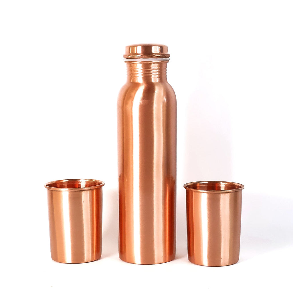 A person pouring water from the leakproof copper bottle into one of the matching glasses.