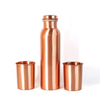A person pouring water from the leakproof copper bottle into one of the matching glasses.