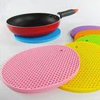 A red silicone hot pot mat being rinsed under water, illustrating its easy-clean feature.