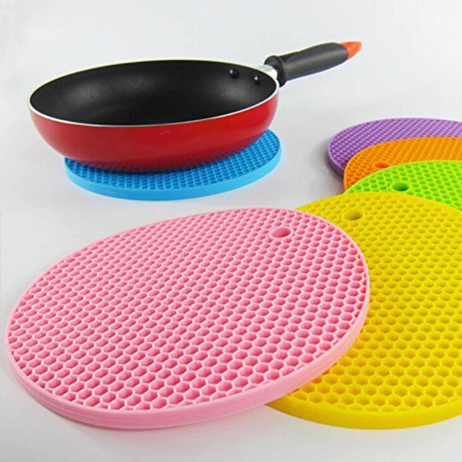 A red silicone hot pot mat being rinsed under water, illustrating its easy-clean feature.