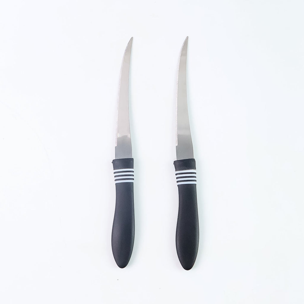 Serrated knife set placed on cutting board with vegetables for kitchen prep
