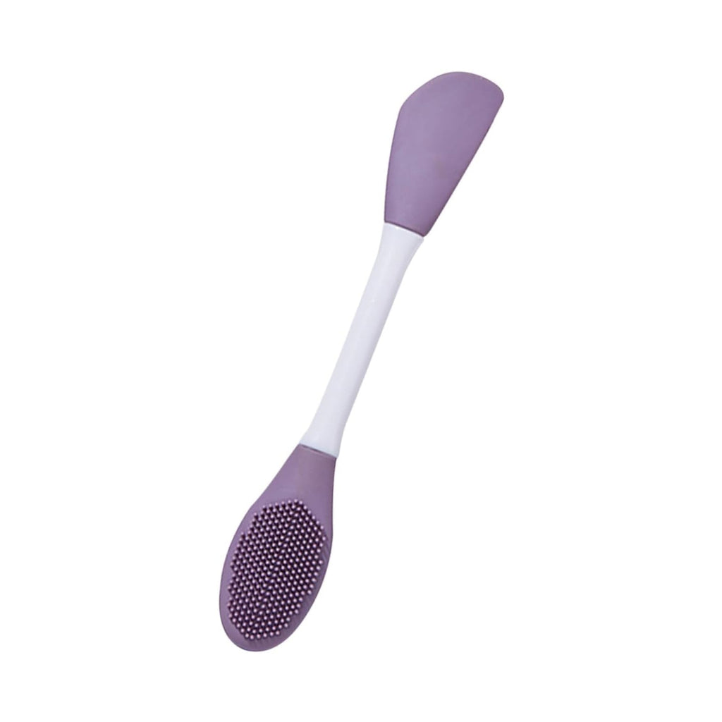 The versatile silicone mask brush shown applying a green clay mask to a face.