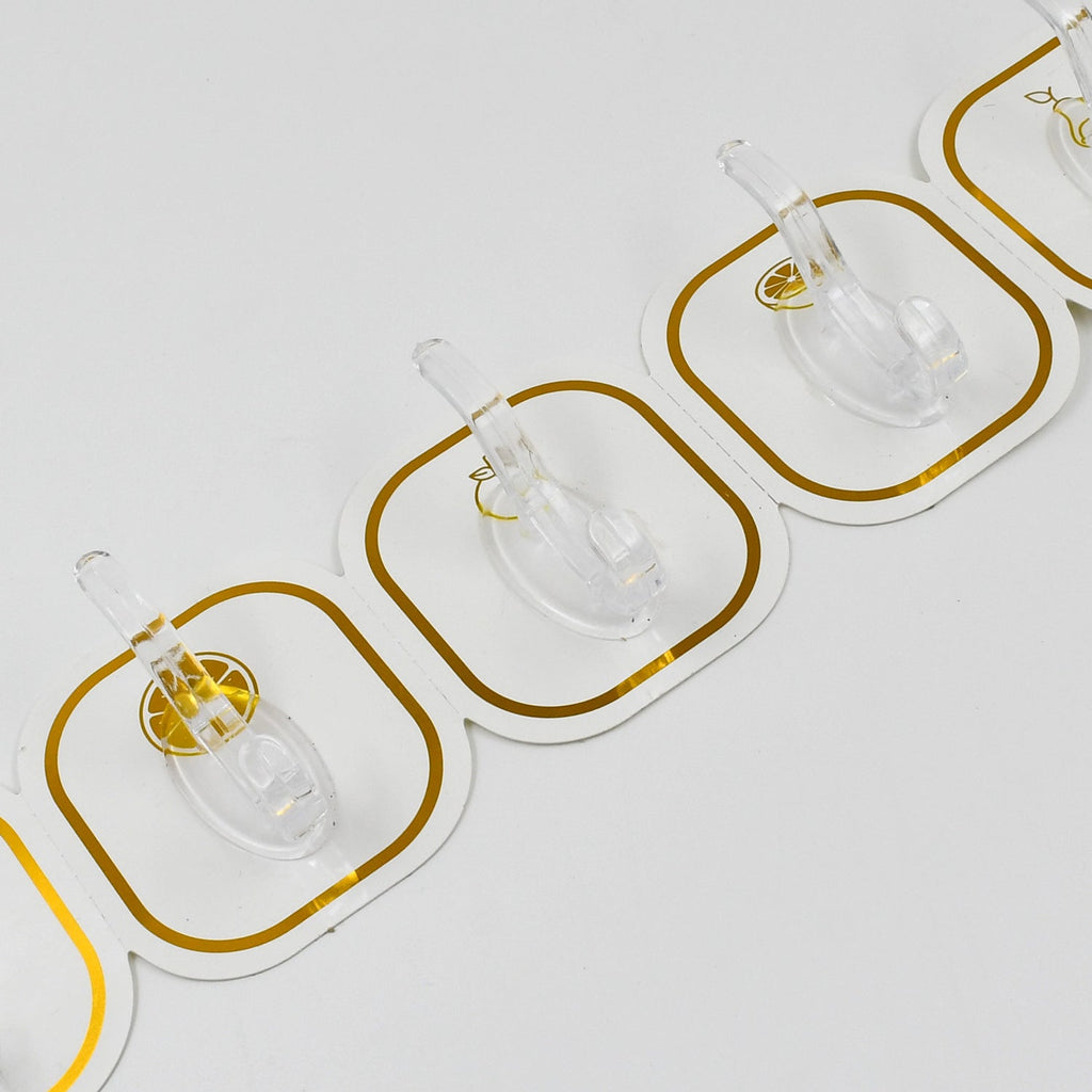 Transparent adhesive hooks installed on a white wall, blending seamlessly with home decor.