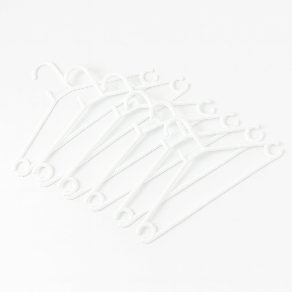 Stack of 6 white plastic clothes hangers ready for use
