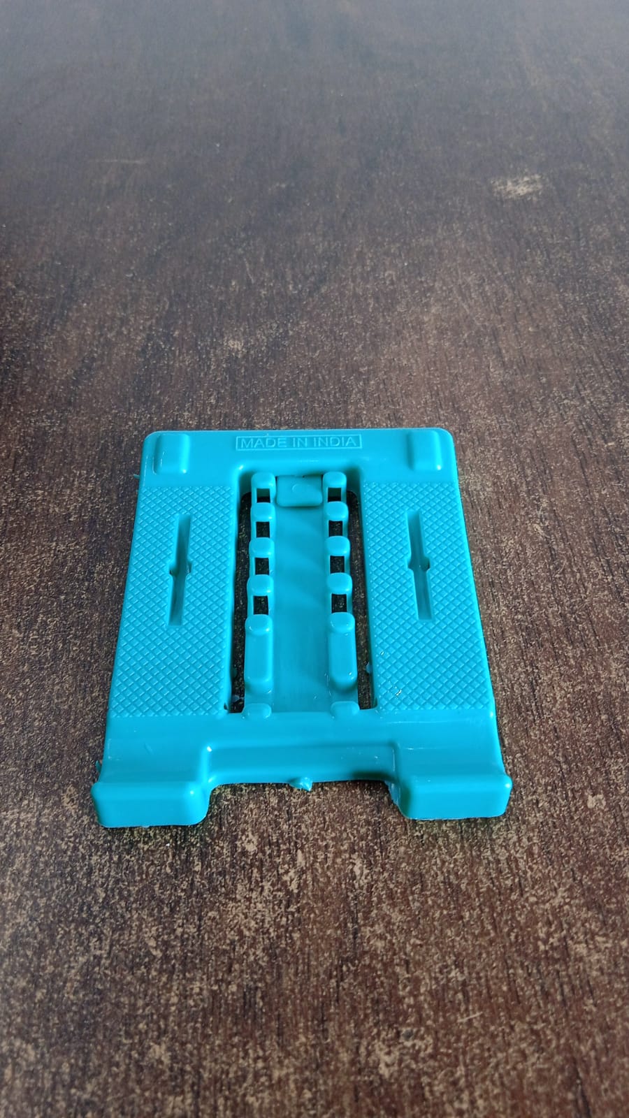 Foldable mobile stand securely holding a smartphone on a desk.