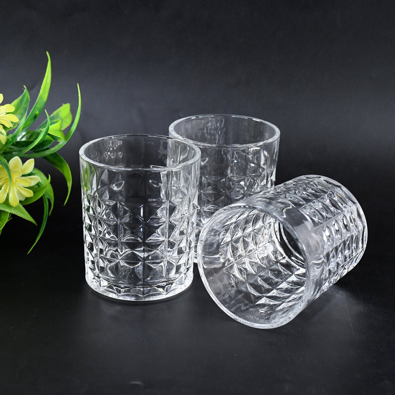A hand holding a diamond-cut glass tumbler, demonstrating its comfortable grip and clear glass quality.