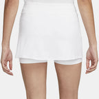 Model running in a white high-waisted athletic skort outdoors.