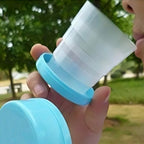 The reusable folding travel cup fully expanded, ready for use with a drink.