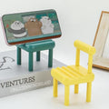 Gambit Mini Chair Phone Stand in natural wood, holding a smartphone upright on a desk.