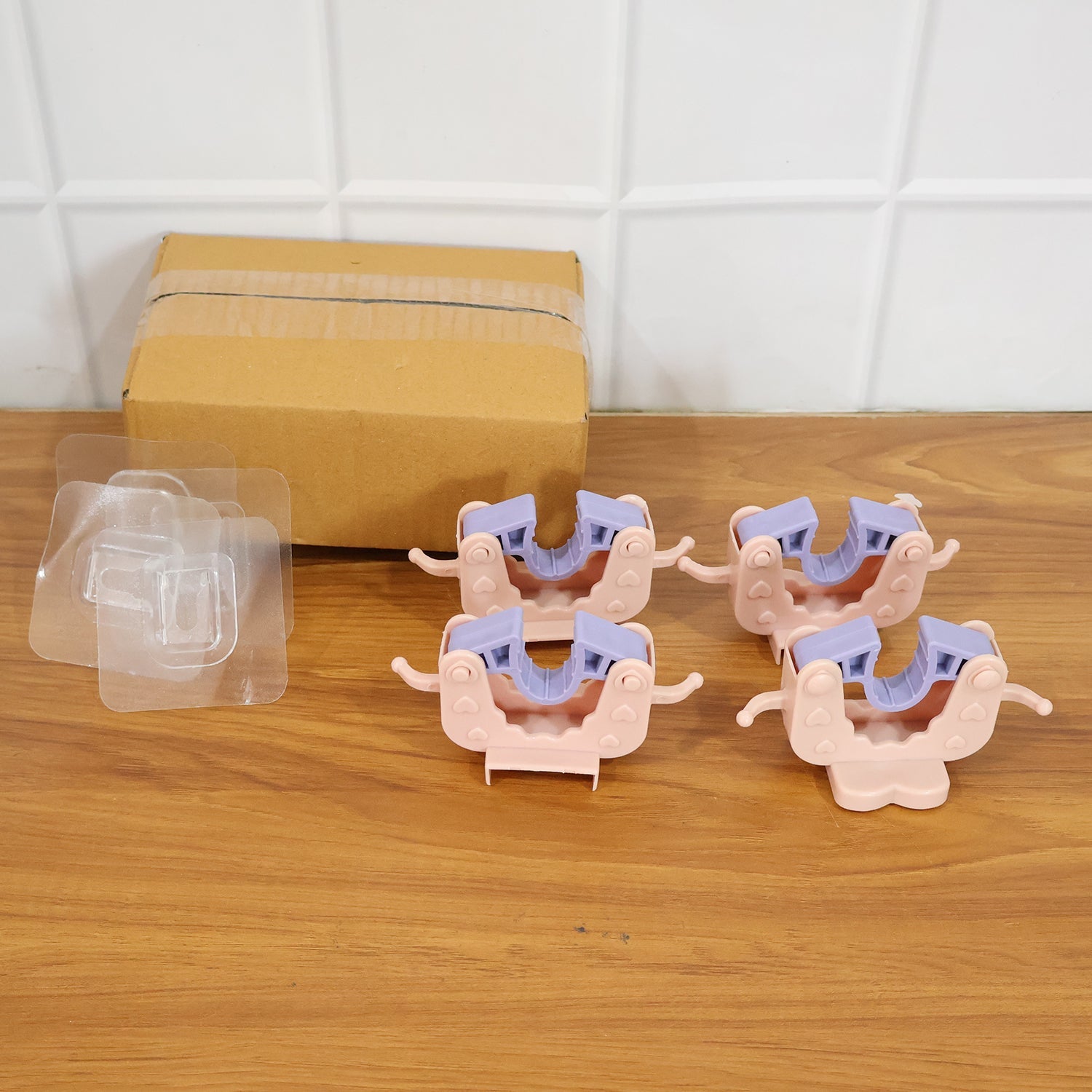 Four broom and mop holder clips mounted on wall organizing cleaning items