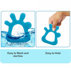 A baby's hand reaches for a soft silicone teether on a cozy blanket.