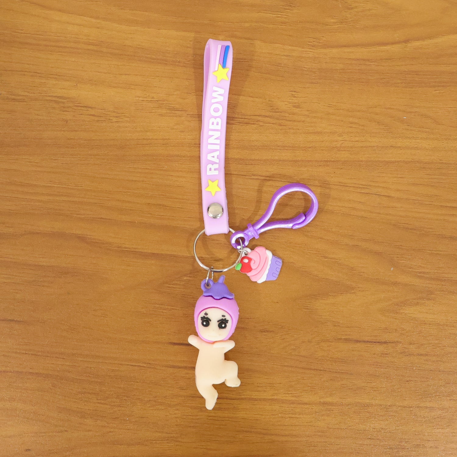 Detailed close-up of doll and cupcake charms on colorful rainbow strap keychain