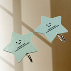 A kitchen scene demonstrating self-adhesive hooks holding spatulas and other cooking tools on a wall.