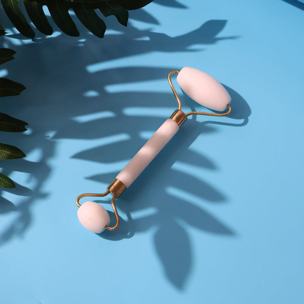 Smooth dual-head facial roller resting on a white surface, ready for use.