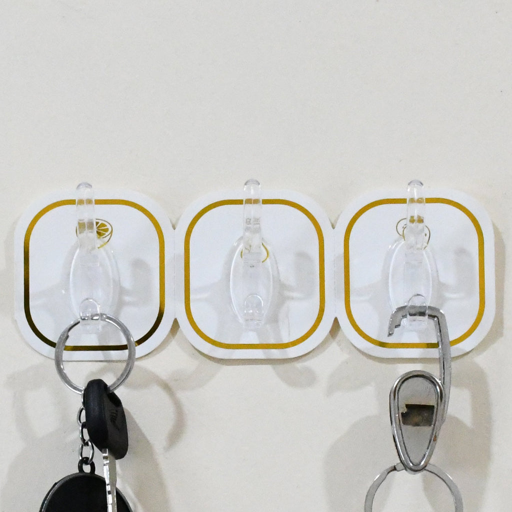 Hand applying a transparent adhesive hook onto a smooth wall surface for easy installation.