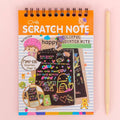 A child's hand scratching a rainbow art scratch book, revealing vibrant colours.