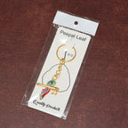Side angle of Krishna flute keychain with peacock feather design in metal