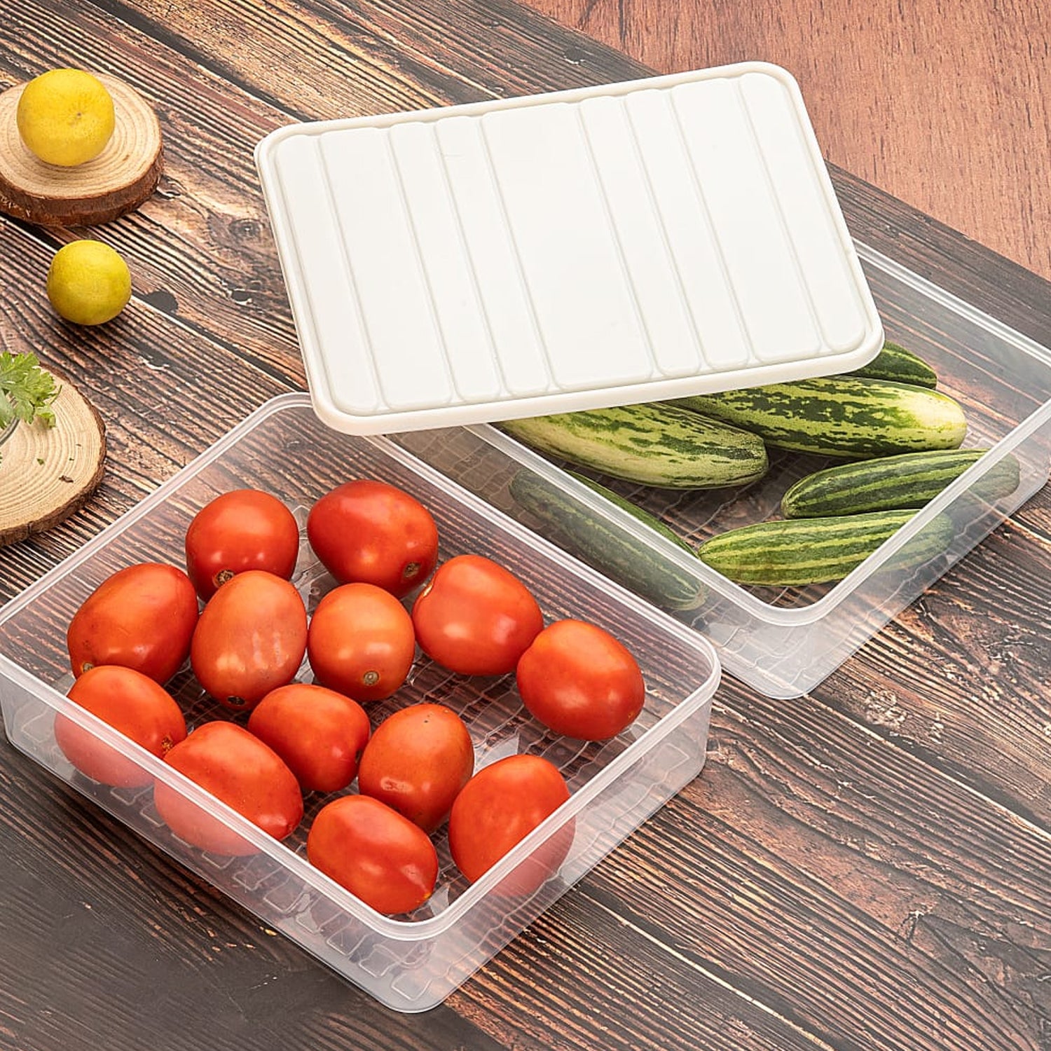 A transparent plastic vegetable storage box with a blue lid, shown filled with various fresh vegetables.