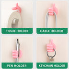 Pink hand-shaped wall clip holder with self-adhesive mounted on surface