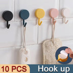 Self-adhesive utility hooks holding kitchen utensils and towels.