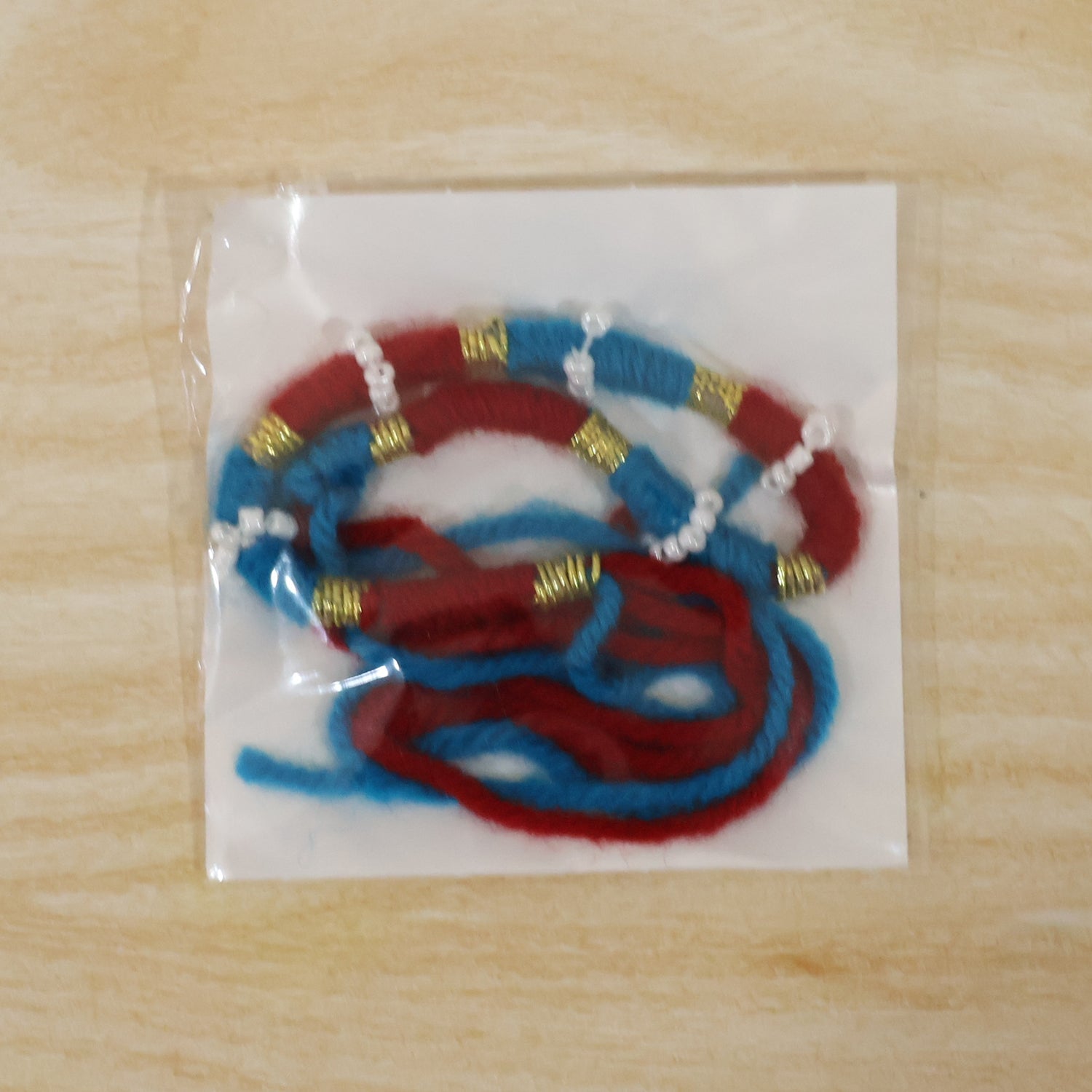 Festive handmade red thread rakhi with pearl detailing