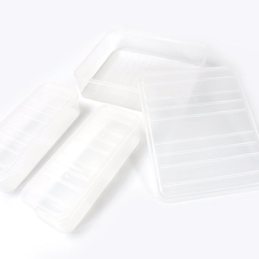 A person placing a transparent plastic food storage container filled with food into a refrigerator.