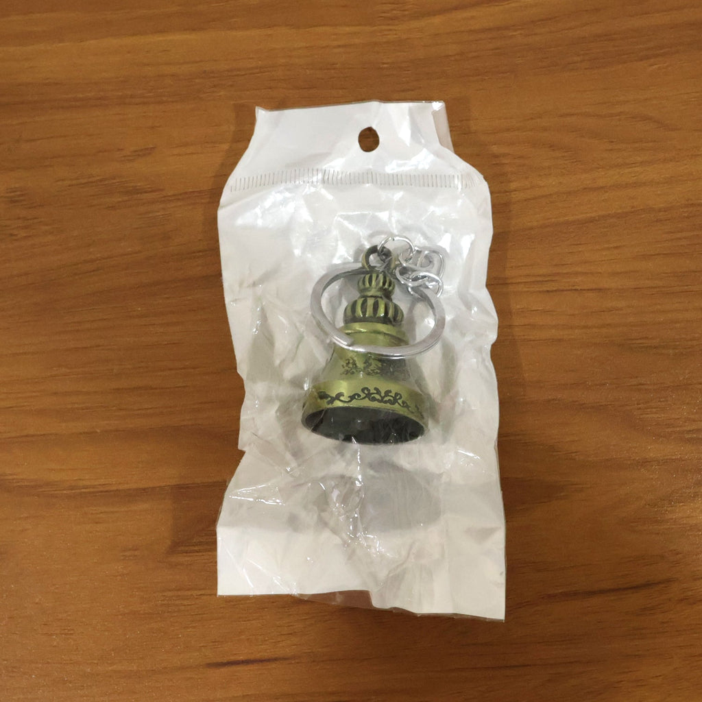 Metal temple bell keychain resting on textured surface background