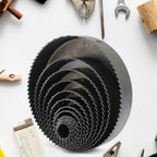 A hole saw attached to a drill, poised to make a cut in a piece of plastic material.