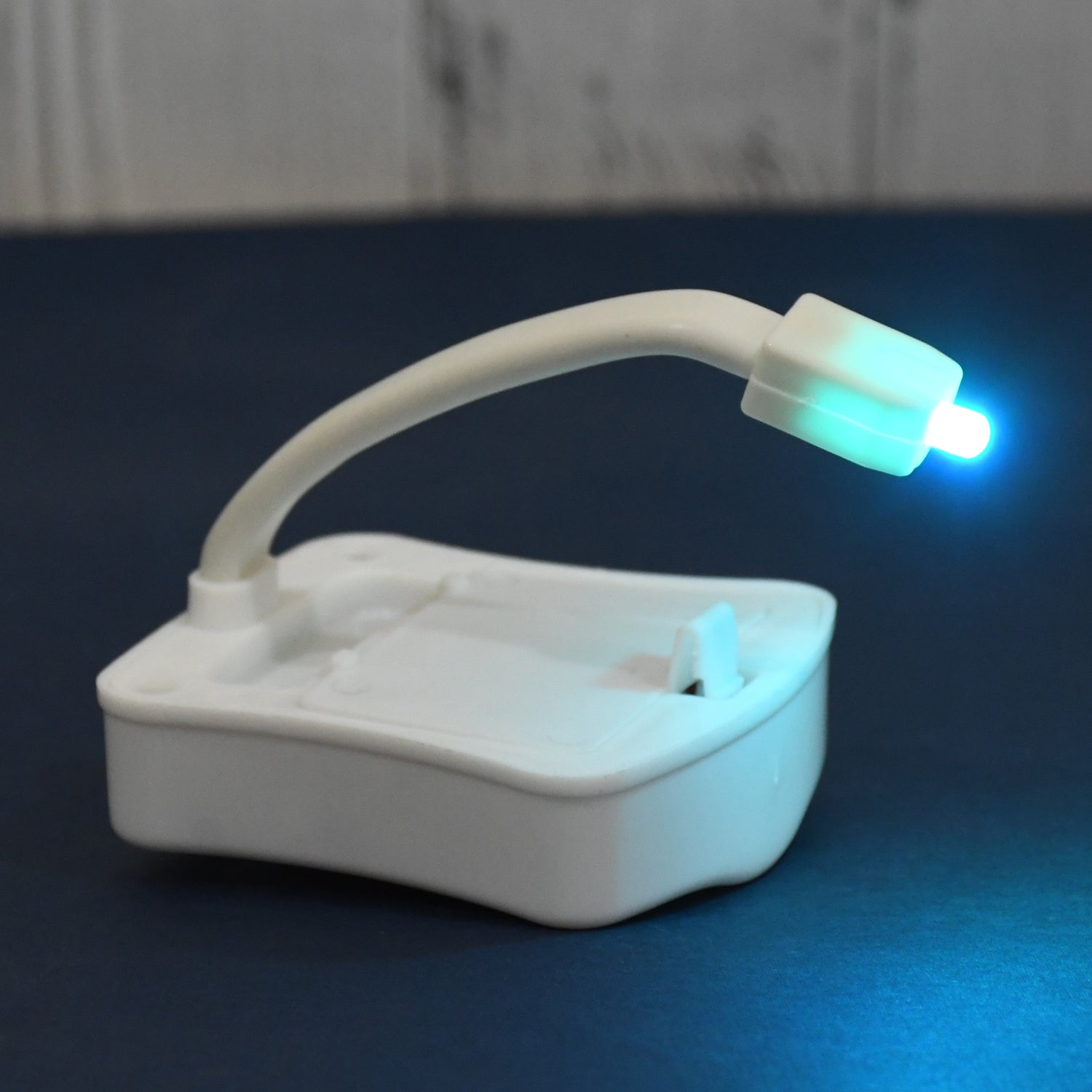The compact LED toilet night light device with its flexible arm for universal fit.