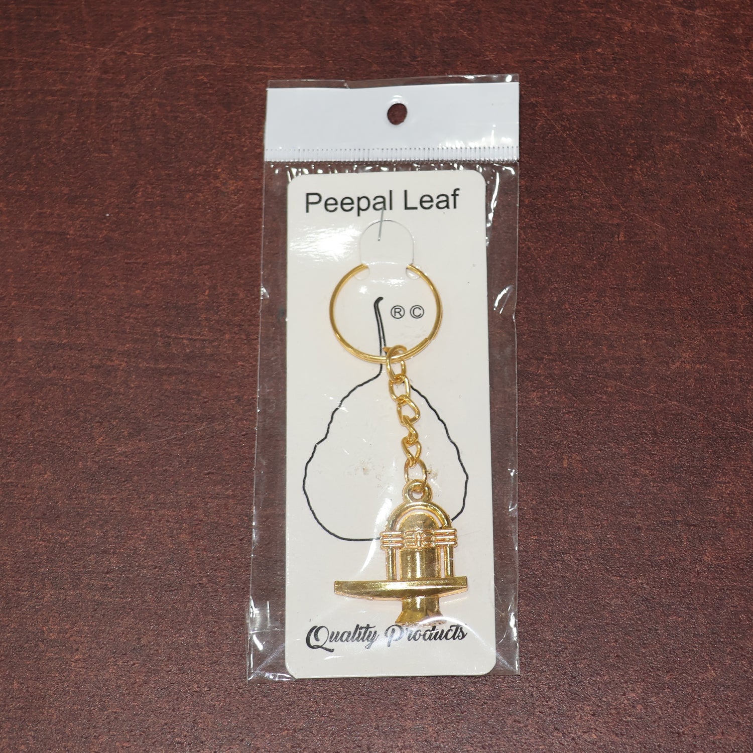 Different angle view of the golden Shivling metal keychain showcasing design