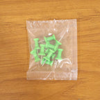 Multiple green push pins arranged showing sharp metal pins