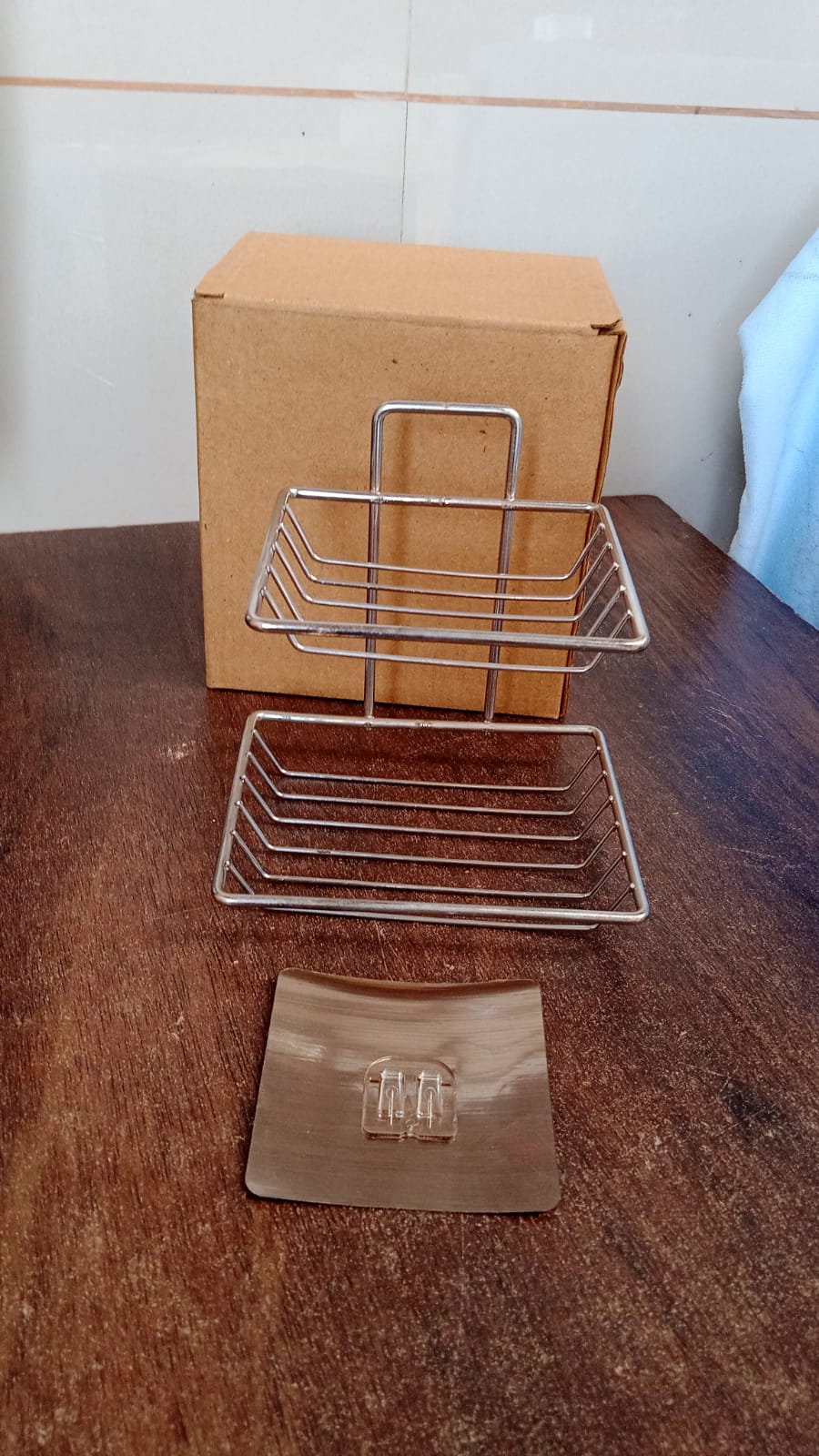 Sleek stainless steel self-adhesive wall mounted soap dish with integrated hooks.