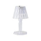 A compact crystal table lamp reflecting light onto a wall.