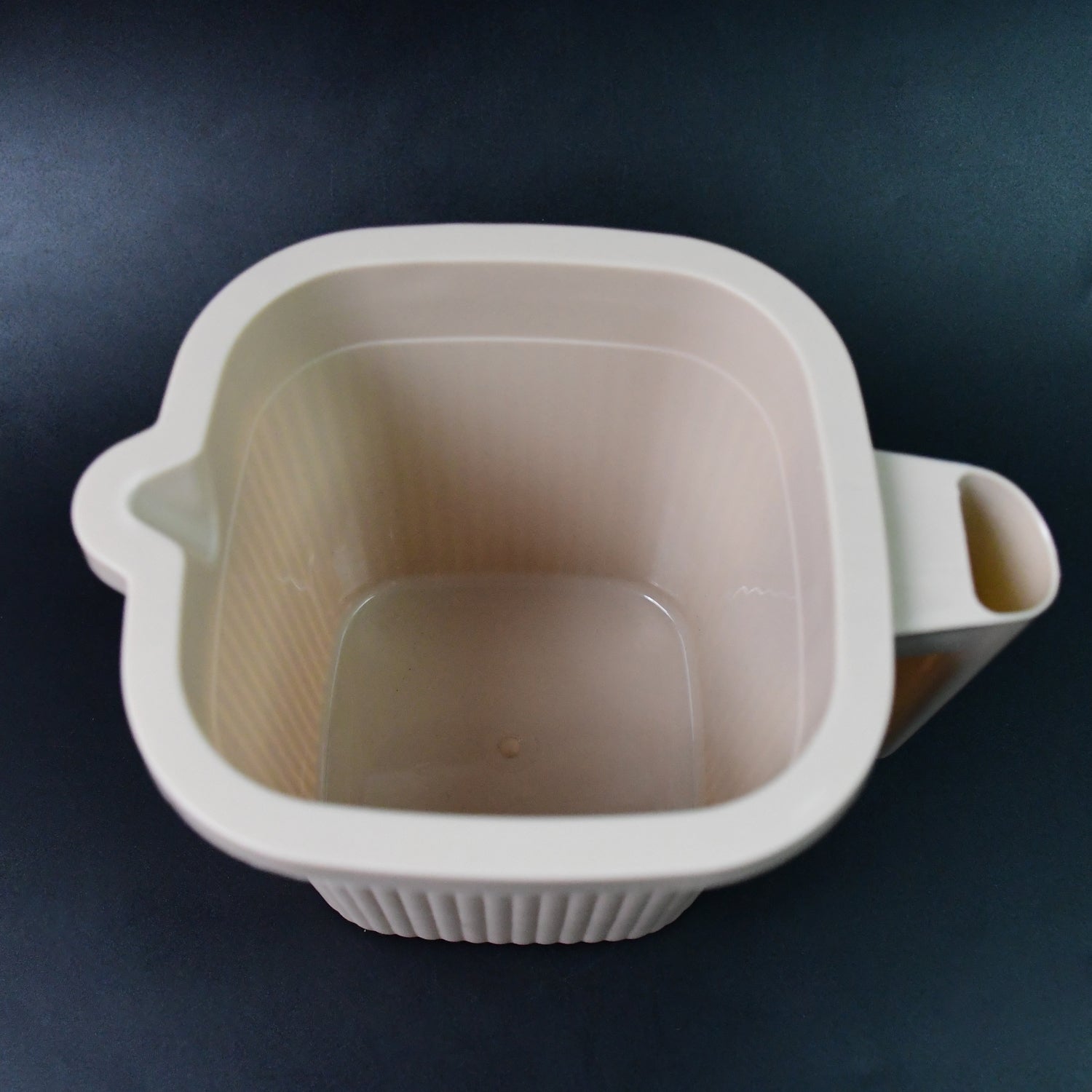 Close-up of a clear Plastic Bath Mug, emphasizing its smooth finish and robust build.