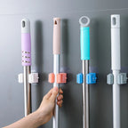 Self-adhesive mop holder securely mounted on a white wall, showcasing its compact design.