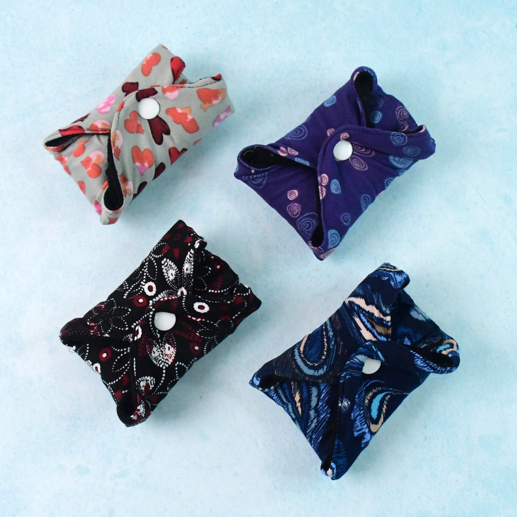Four reusable cloth sanitary pads in assorted prints laid out flat for daily hygiene