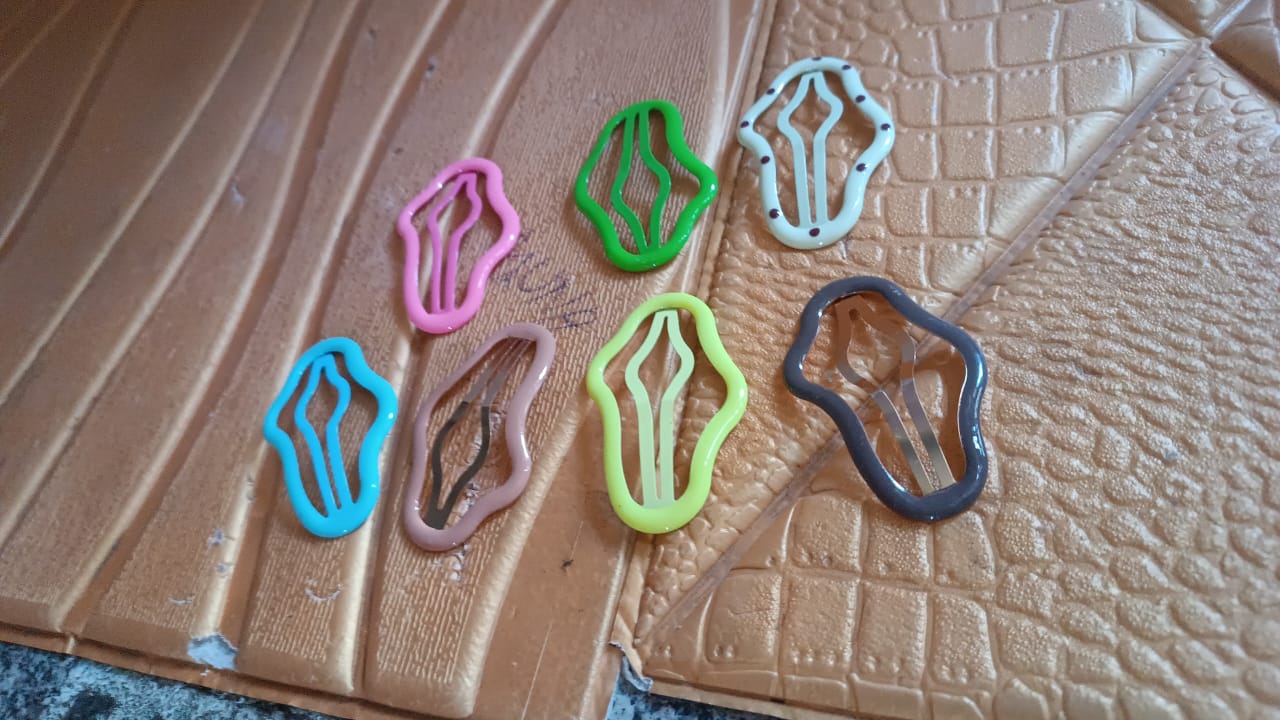 Hand holding a selection of colorful metal hair clips