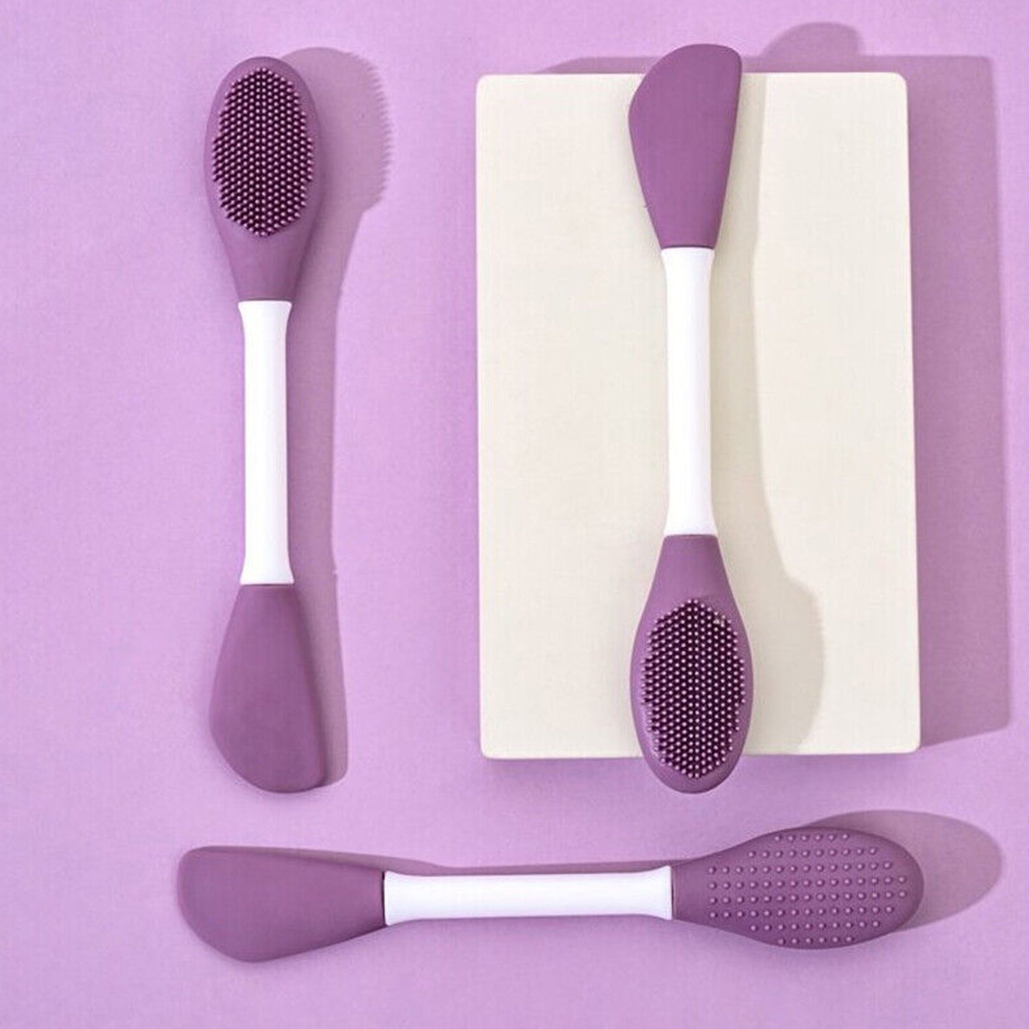 Double-headed silicone mask brush with a pink silicone head and white handle.