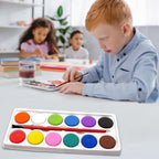 Open watercolor kit displaying 12 colorful paint cakes and an included brush, ready for use.