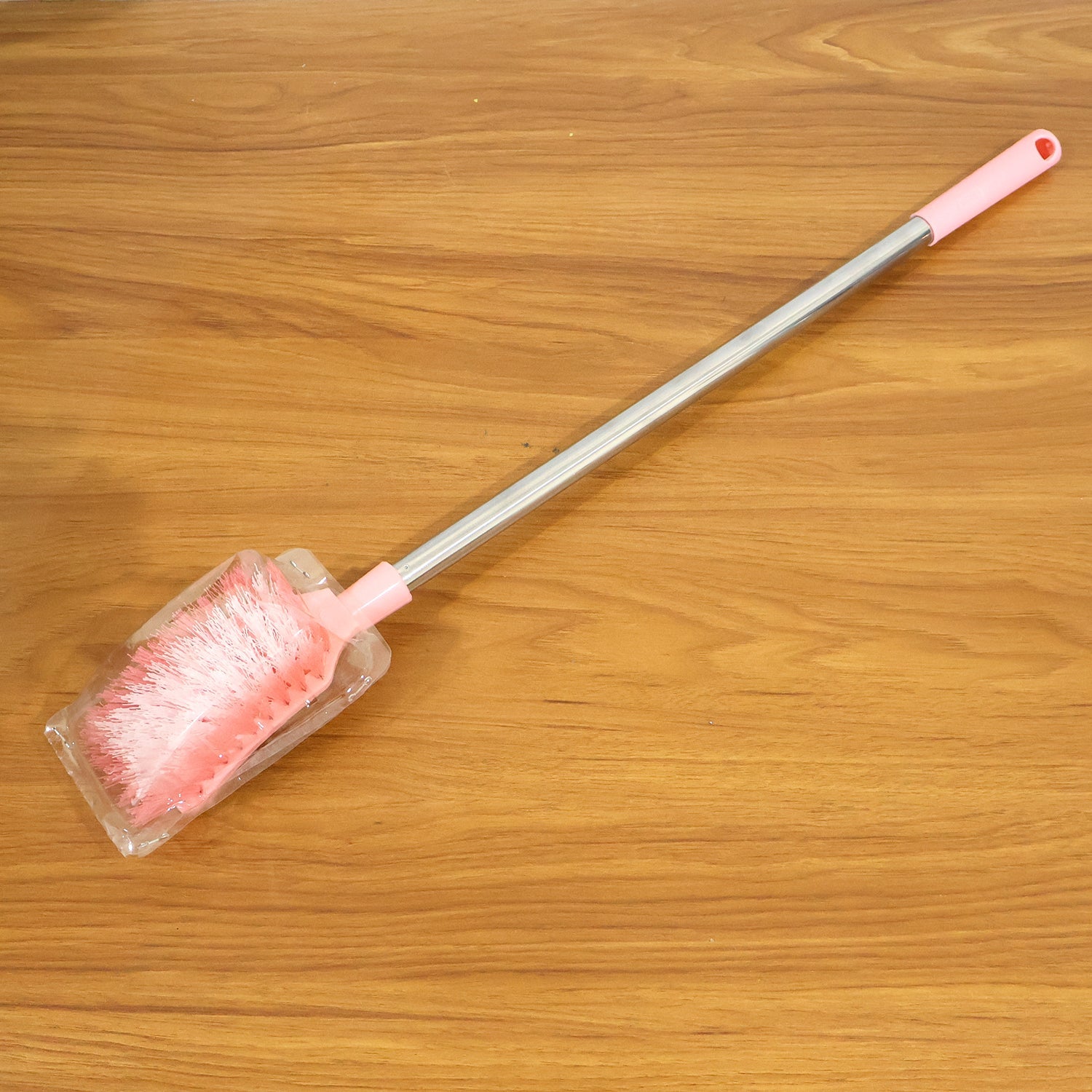 Toilet brush in use cleaning toilet bowl with long handle and splash-resistant head