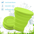Person enjoying a drink from a silicone foldable mug in an outdoor setting.