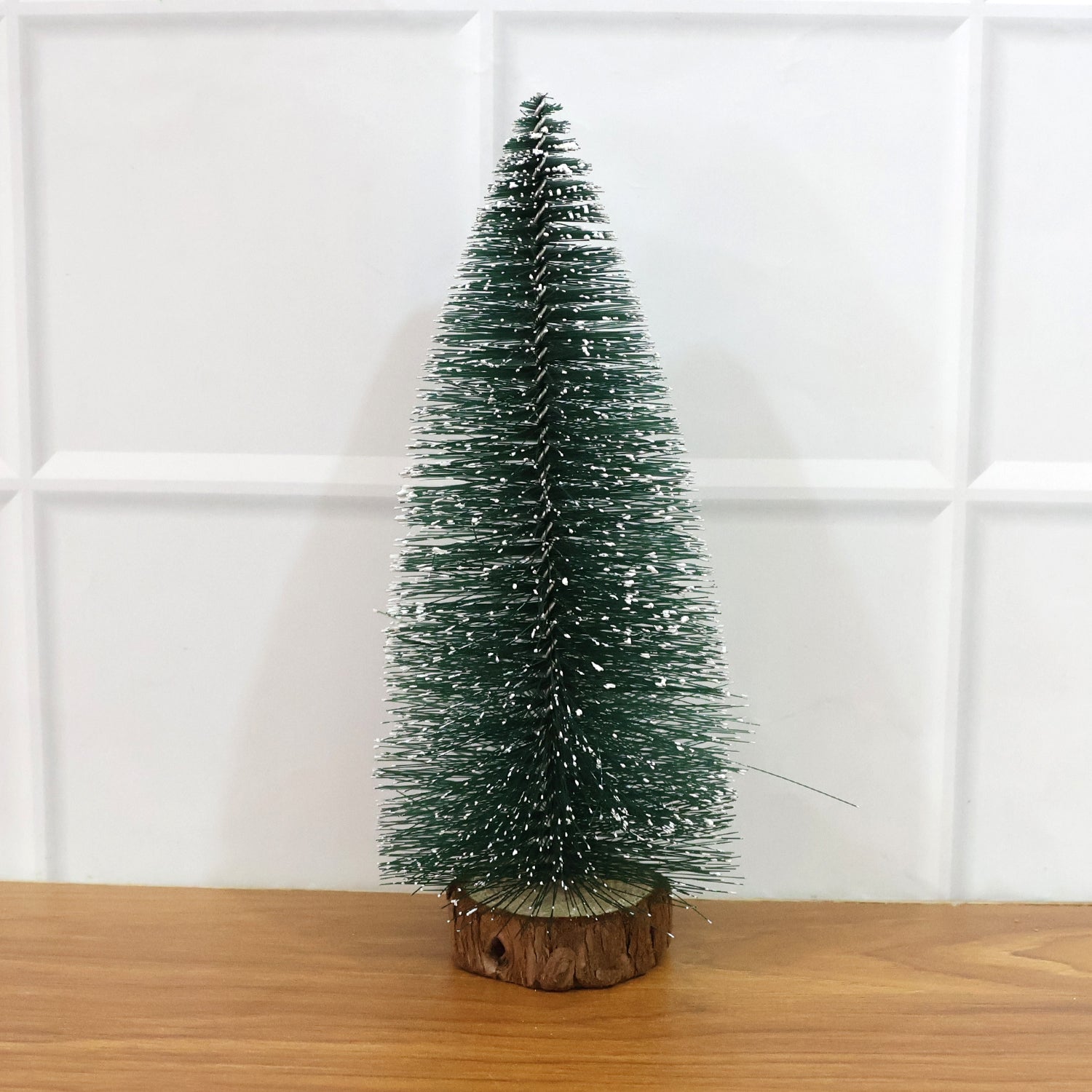 Miniature green Christmas tree with snow effect and sturdy wooden base for festive decor