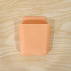 Wall mounted storage pocket holding remote control and mobile phone for easy access