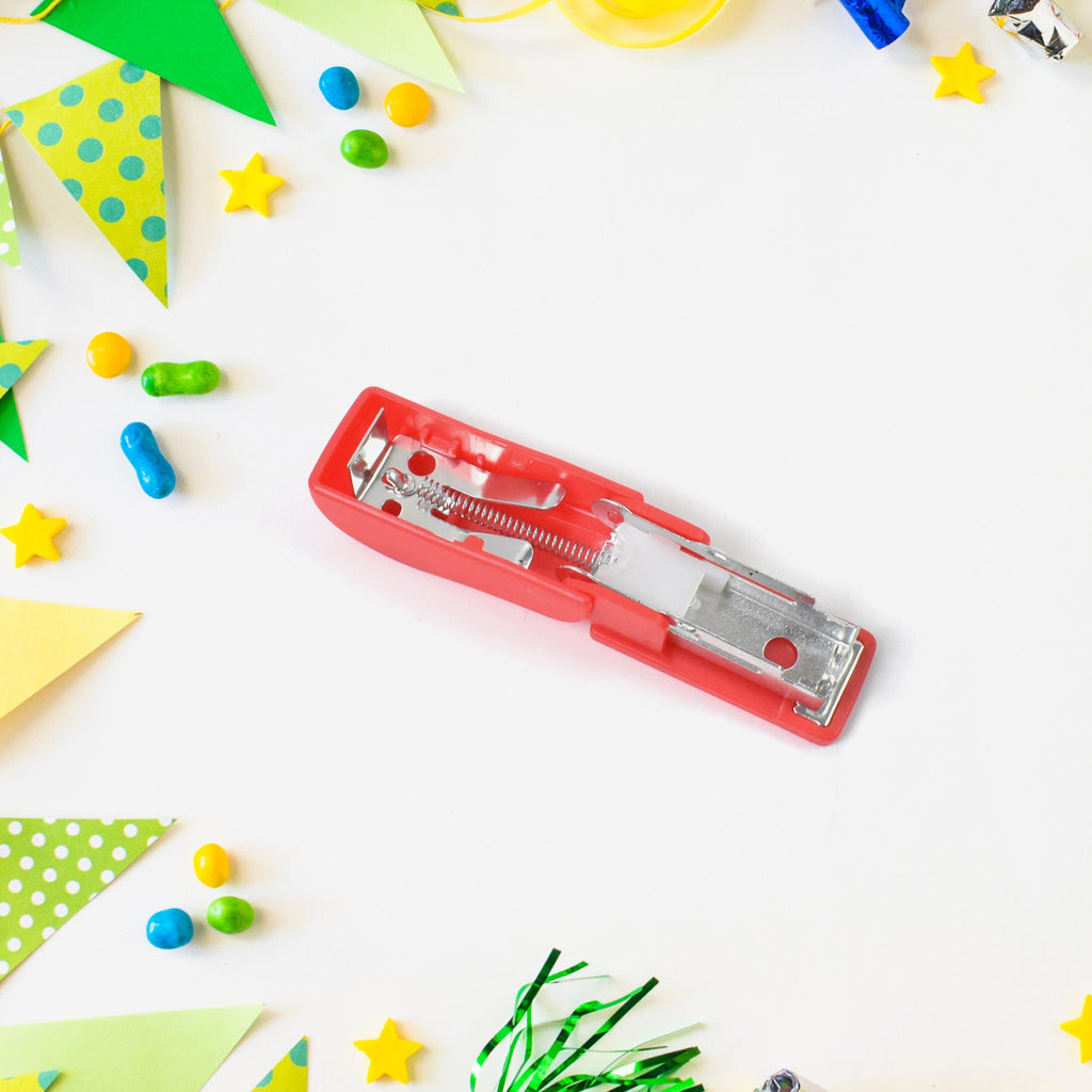 Hand holding a compact FiloDesk mini stapler, demonstrating its small size.