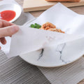 Oil-absorbing cooking paper sheets on a plate with fried food, reducing grease.